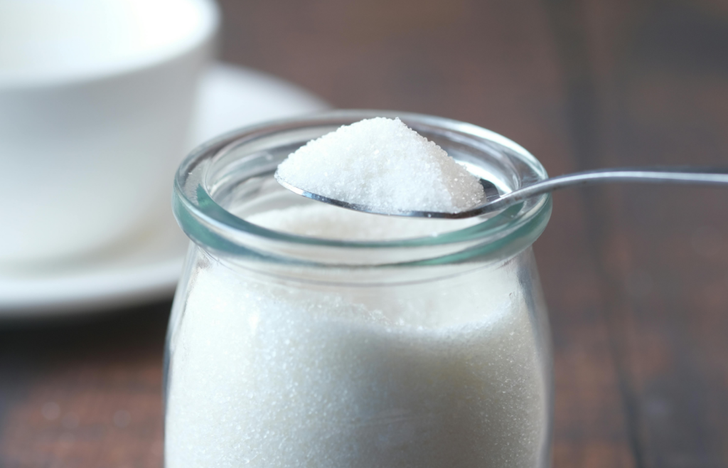 A glass jar filled with white granulated sugar