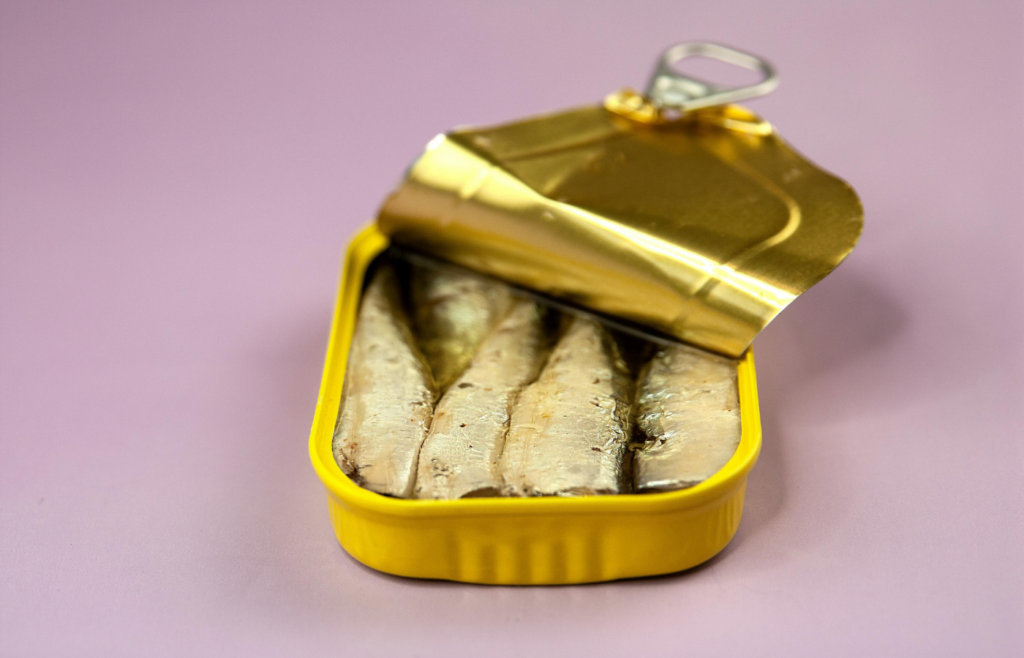 Canned fish in package on lilac background