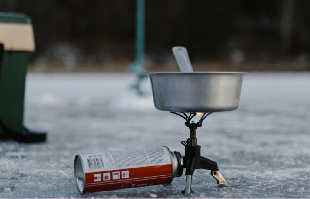 A pile of canned food next to an unused camp stove