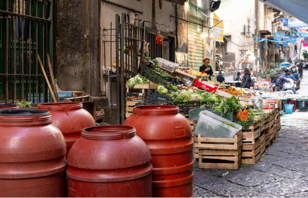 A street with many red barrels and vegetables