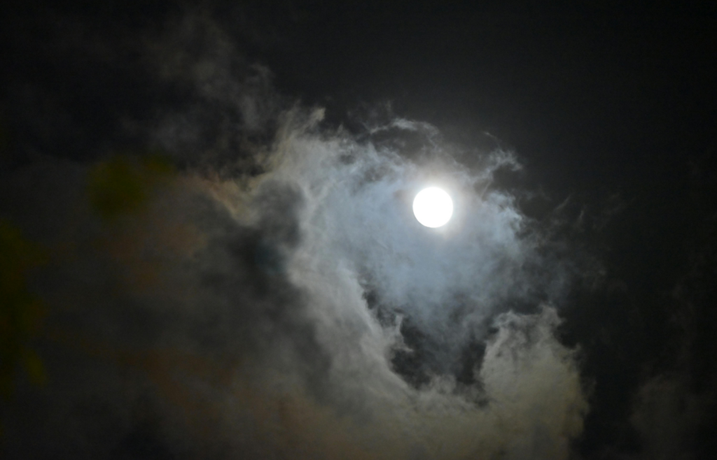 Full moon surrounded by clouds in night sky