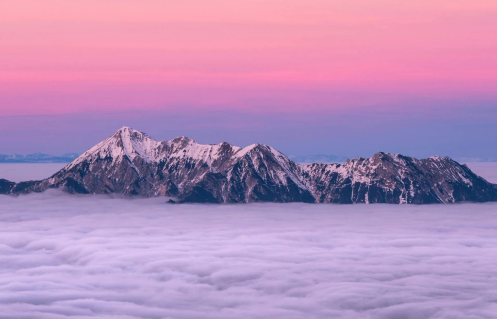 A snow-covered summit of Mauna Kea with tropical scenery below