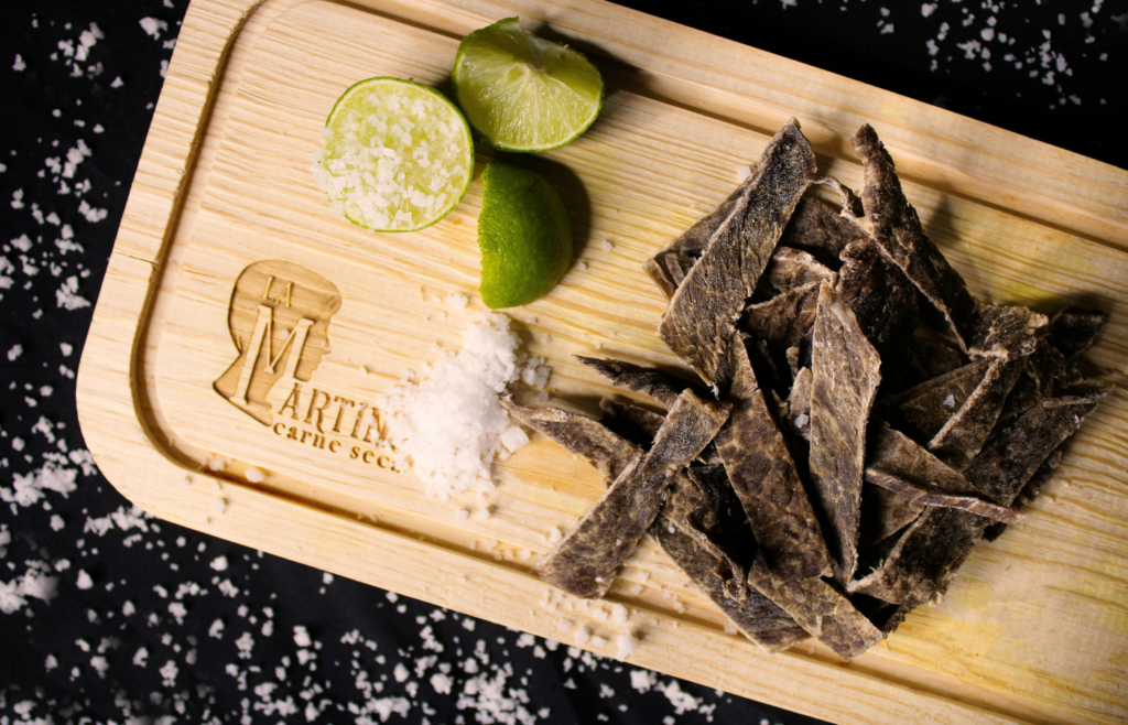 Slices of meat on a wooden chopping board with Lime and Salt