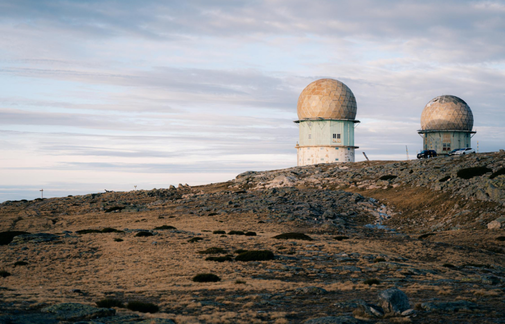Two geodesic radar domes on rocky hilltop