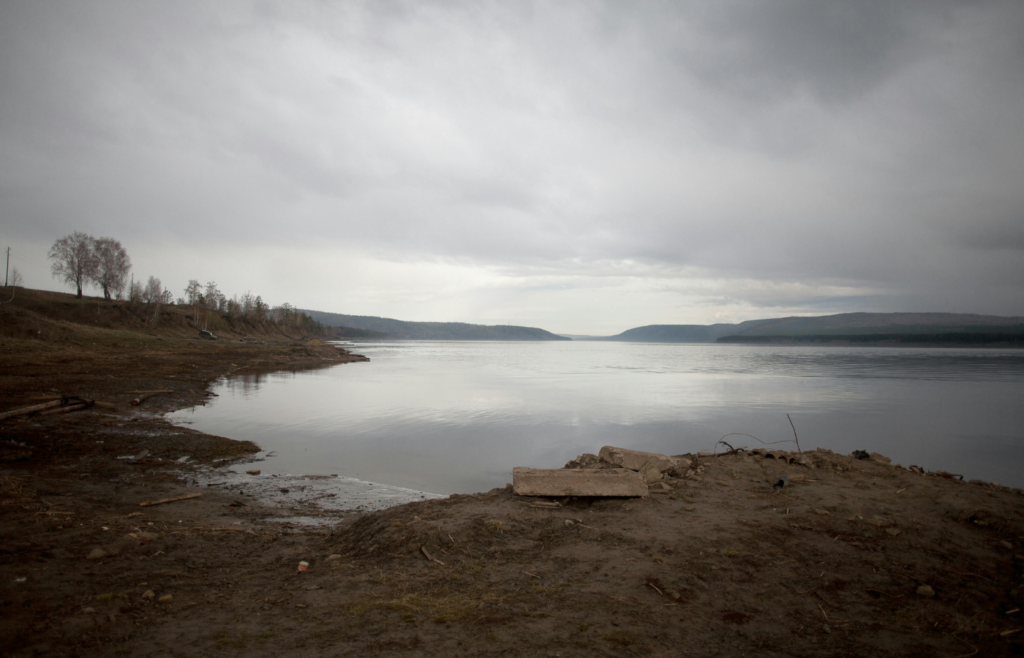 Peaceful embankment of endless river in gloomy weather