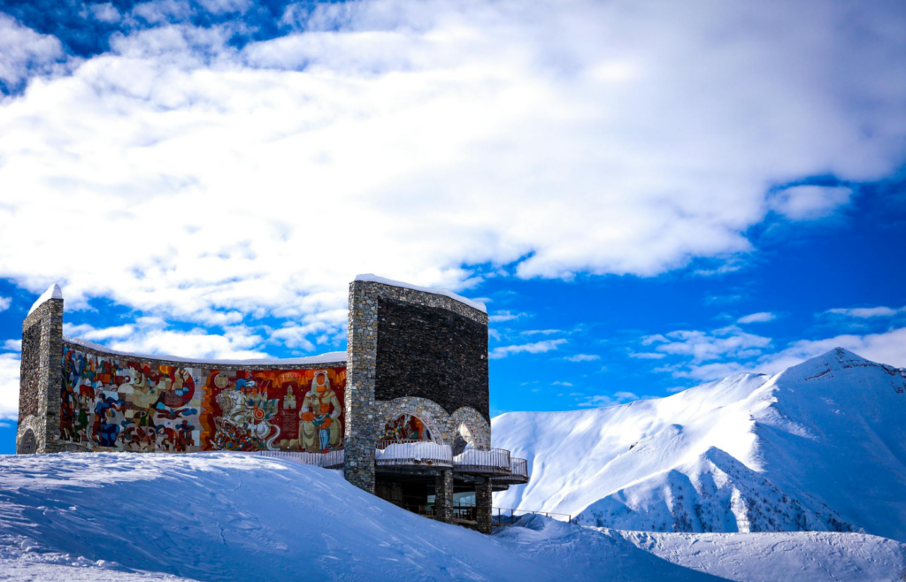 Mountain monument with colorful murals against snowy peaks