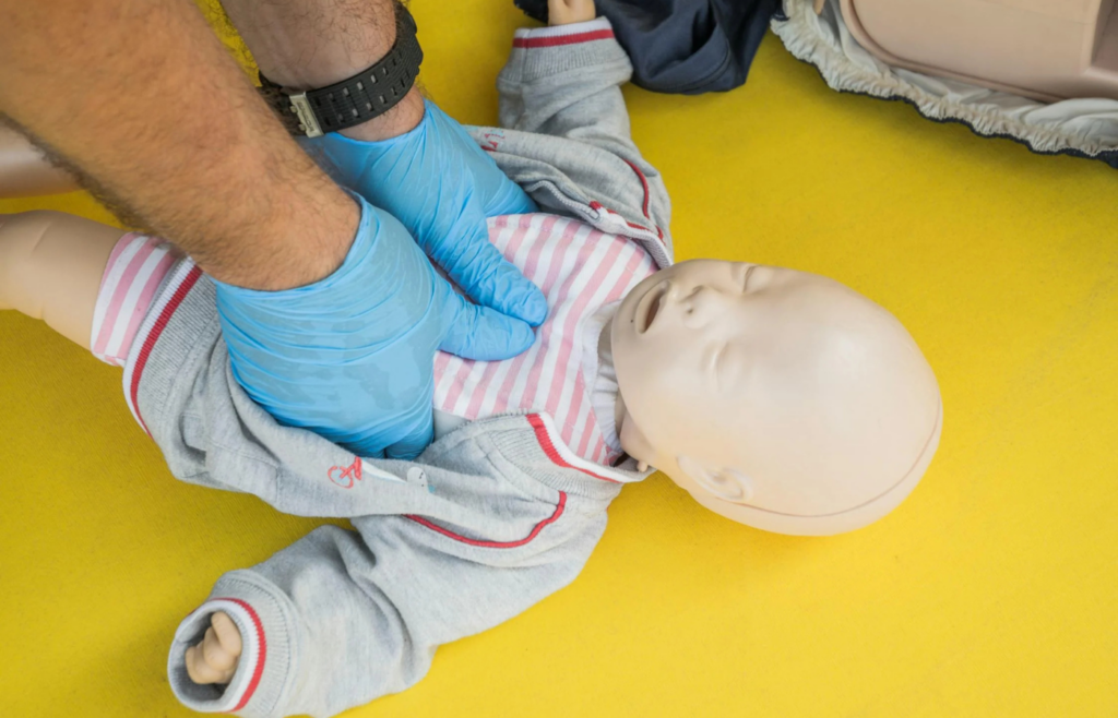 Hands performing CPR on a training mannequin