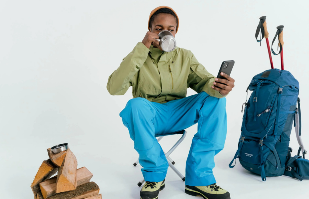 Camper drinks coffee while checking phone