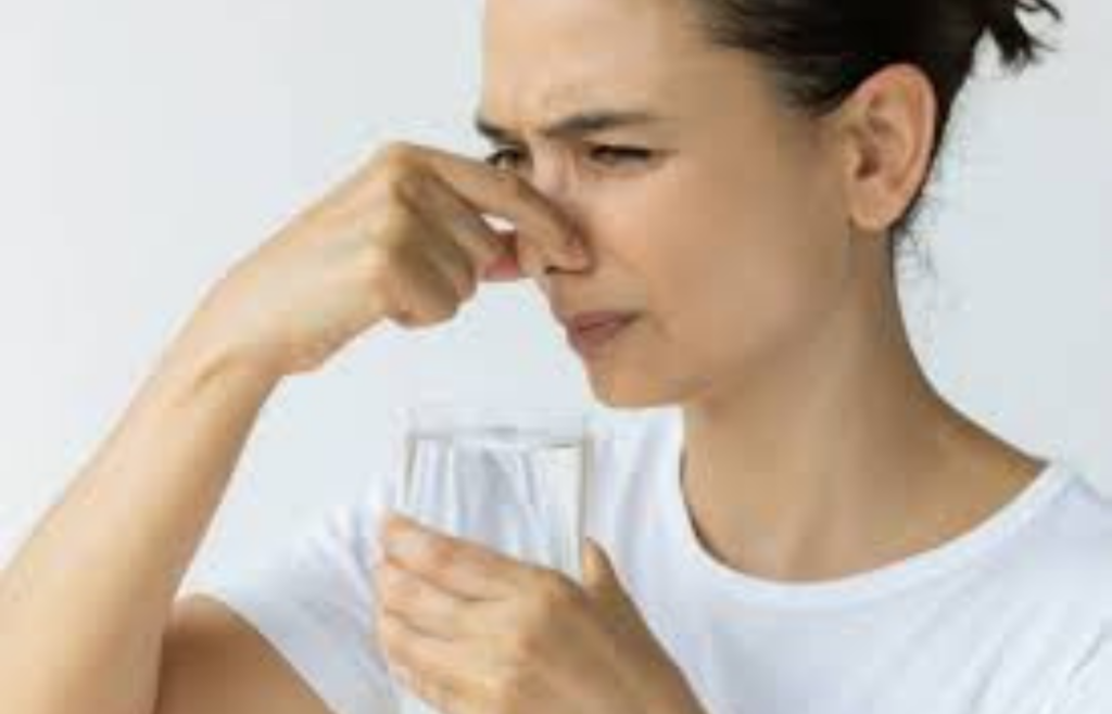 Person holding nose near a glass of water