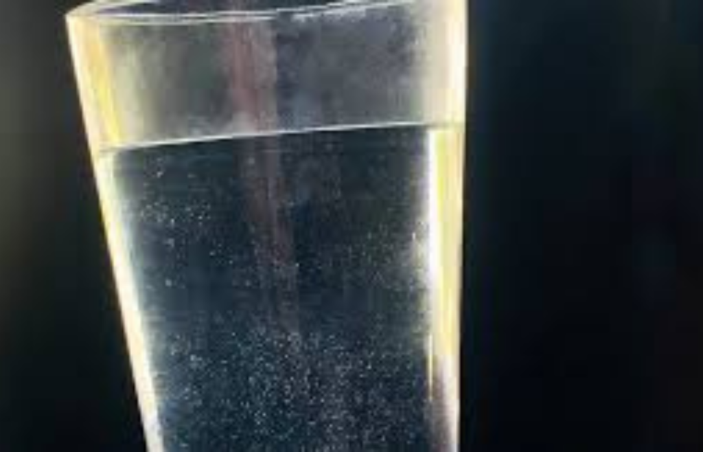 Glass of water with visible particles settling at the bottom