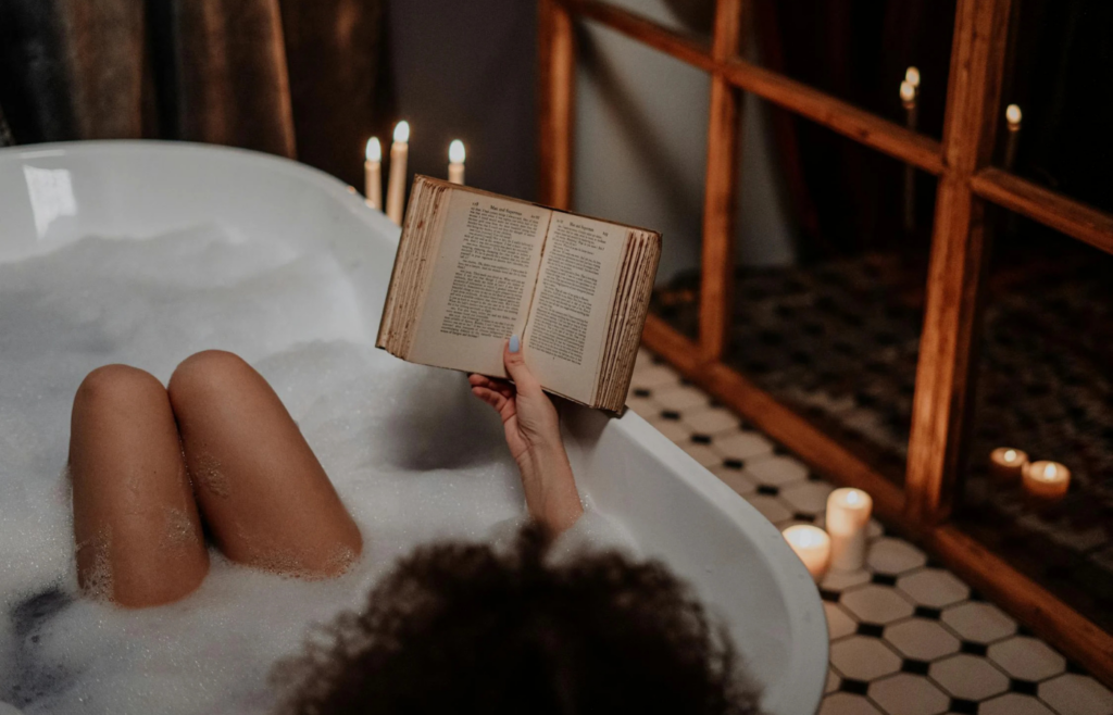 A lady is taking a shower while reading a book