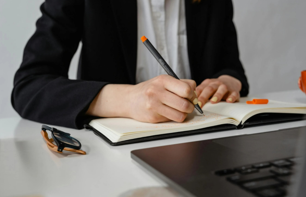 Person writing in a planner at a desk