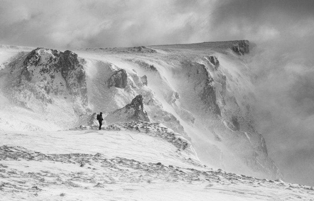 A lonely man among the snowy mountain cliffs