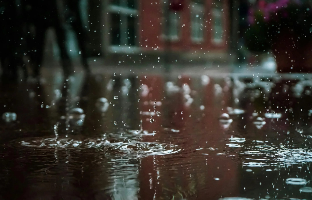 Raindrops splash on a reflective urban street