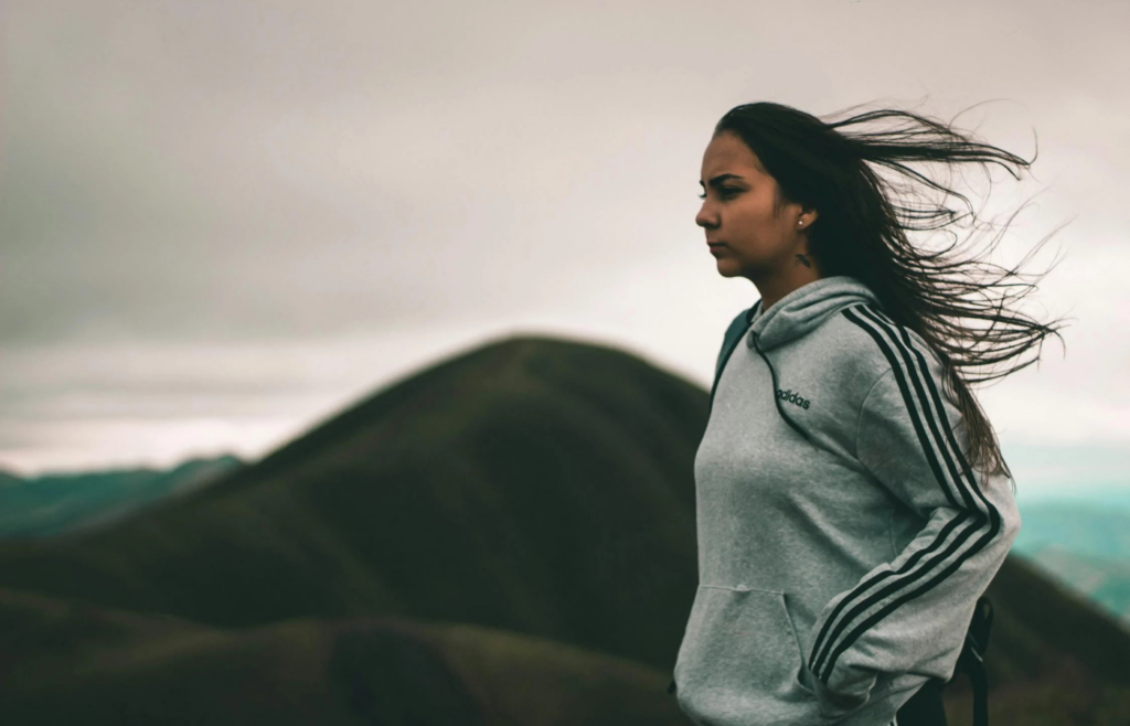 Woman on a windy mountain, hair flowing, eyes fixed ahead