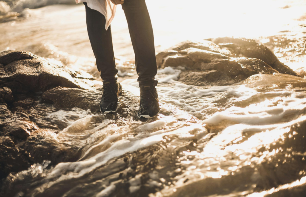 Person stepping cautiously through shallow, murky water