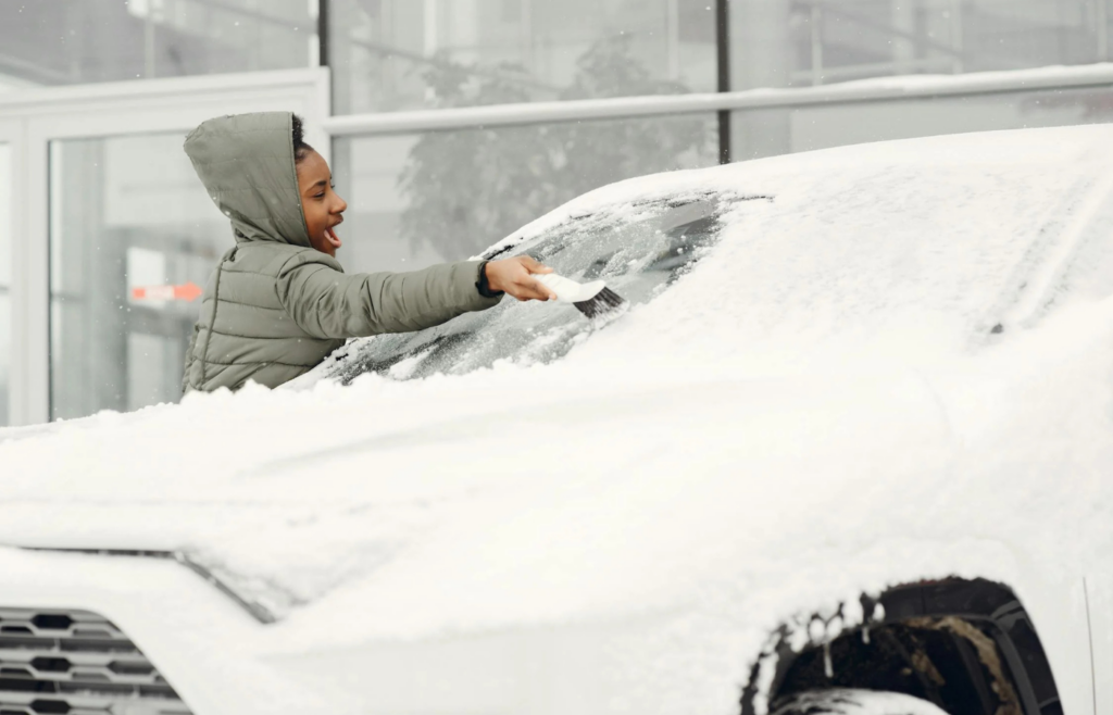  Ice scraper and snow brush resting on a snowy windshield