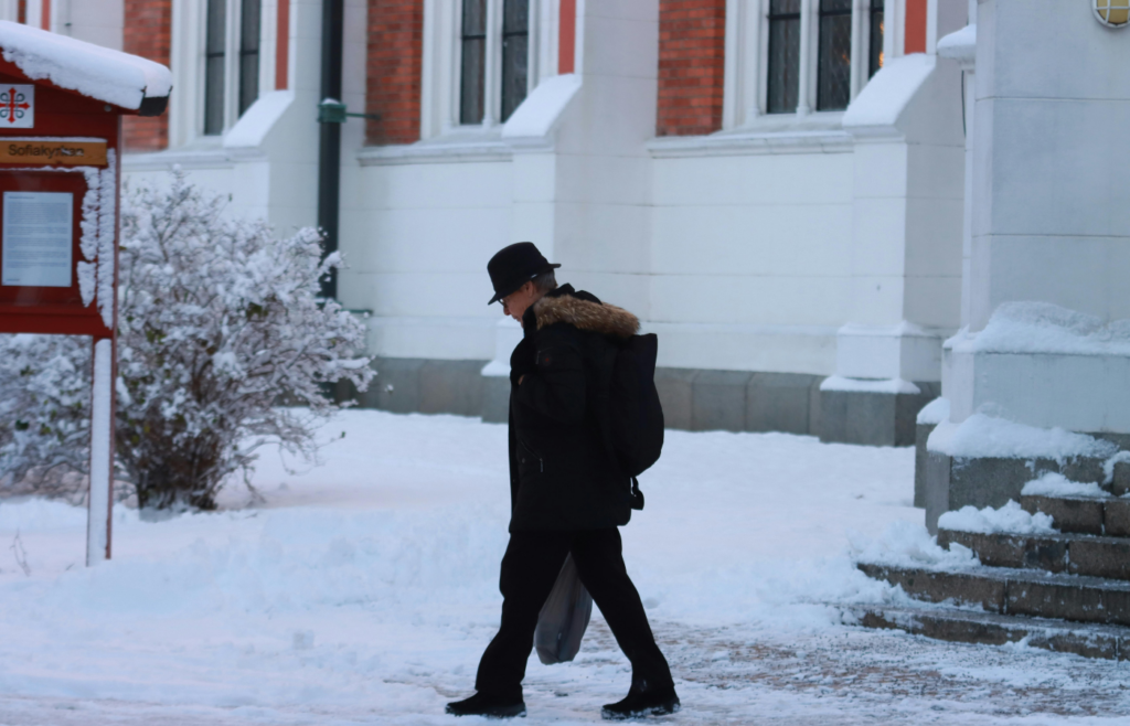 Man in Black Coat Walking on Snow Covered ground