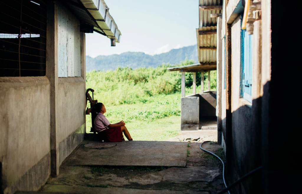 Woman sitting beside hand water pump
