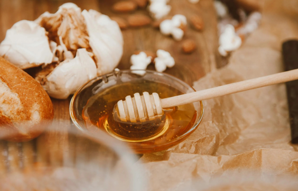 A jar of honey with a wooden dipper on a kitchen counter