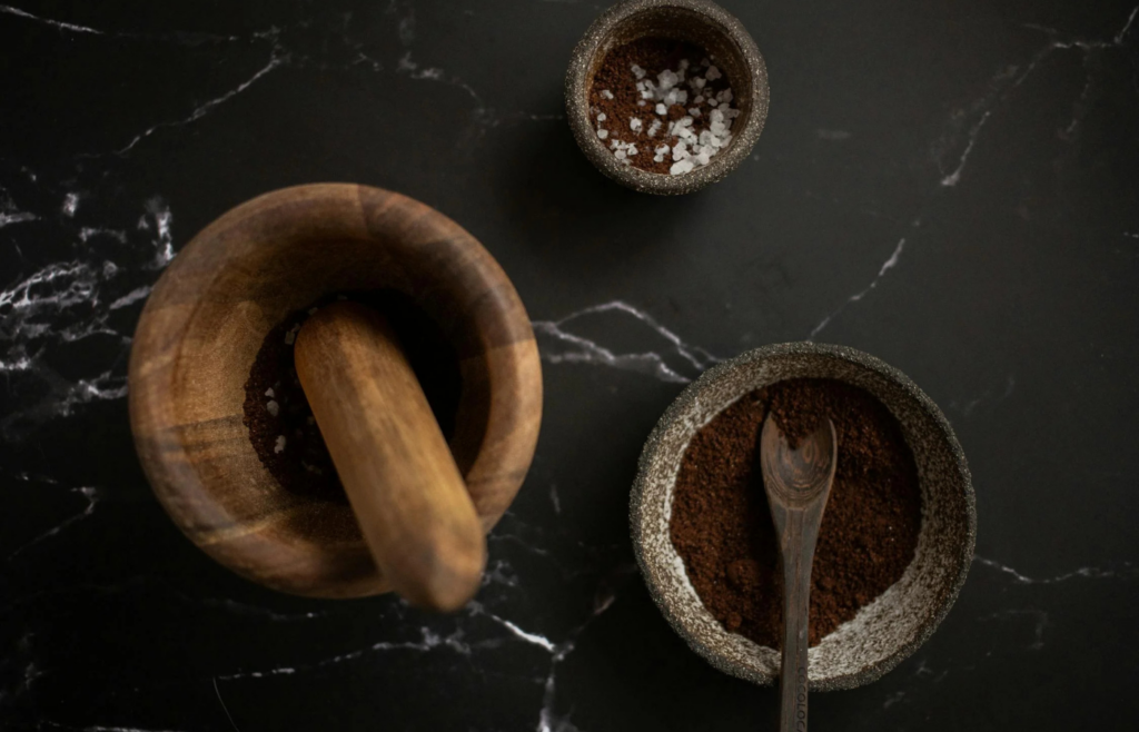 A wooden mortar and stone bowls with spices
