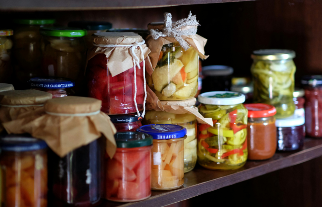 A shelf full of jars of pickles and other food
