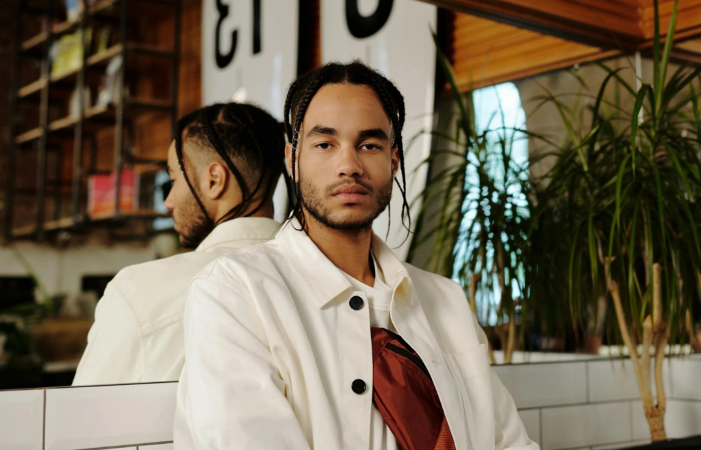 Person with braided hair in white jacket indoors