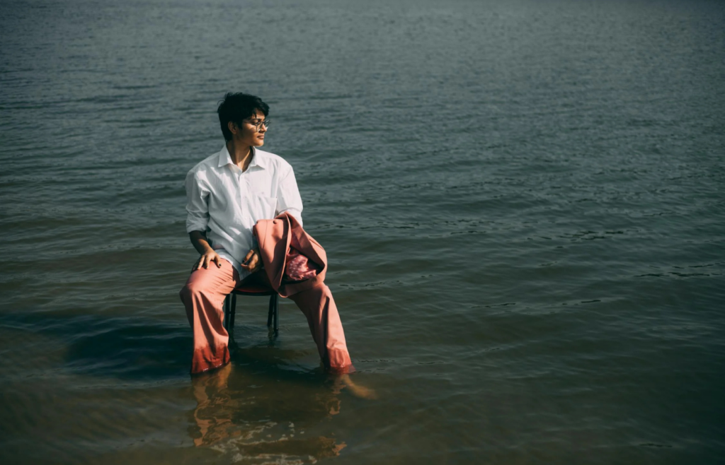 An individual sitting peacefully by a lake, gazing into the distance