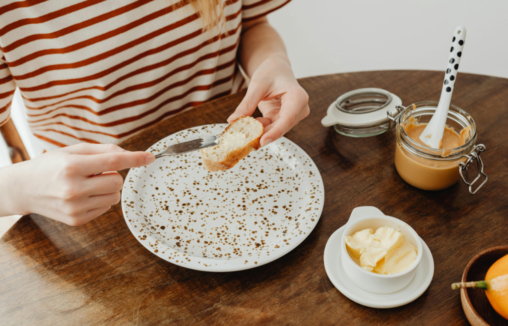 Person spreading butter on sliced bread