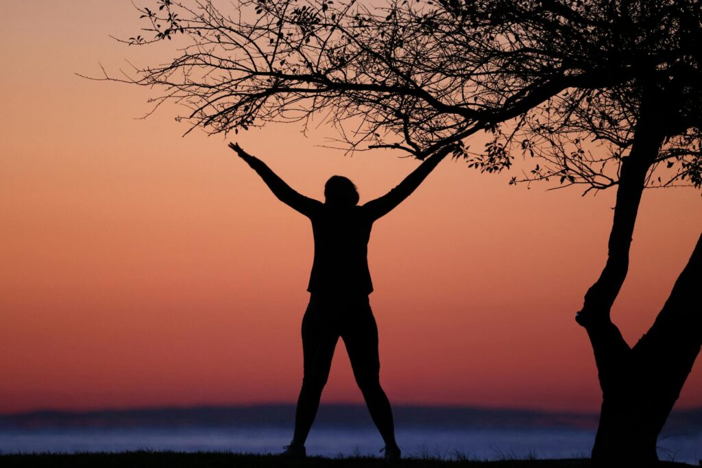 Person standing with arms raised in a "Y" shape
