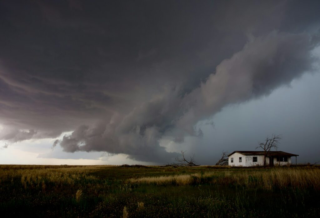 A huge storm cloud approaches a small house.
