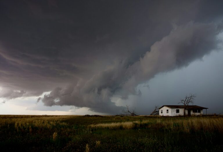 A huge storm cloud approaches a small house.